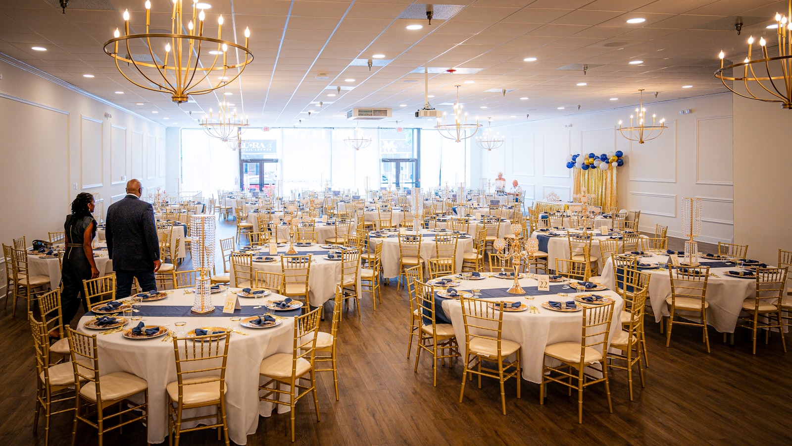 Elegant banquet hall set for a wedding reception with multiple round tables, white linens, and chiavari chairs